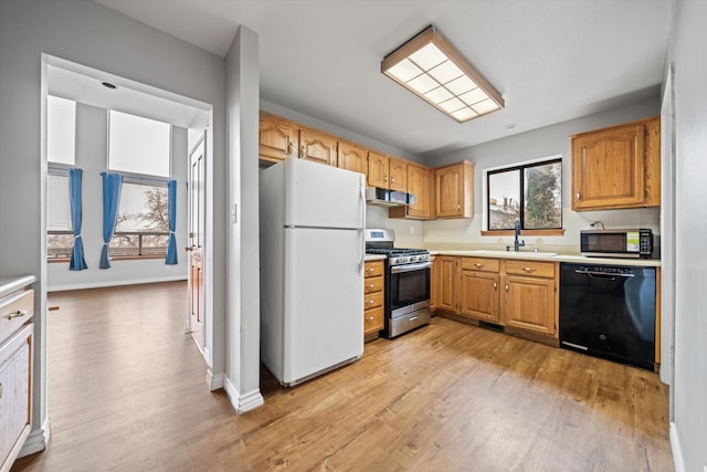 kitchen featuring sink, light hardwood / wood-style floors, exhaust hood, and appliances with stainless steel finishes