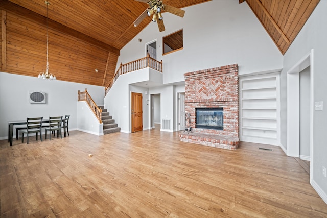 unfurnished living room with light wood-type flooring, wooden ceiling, a fireplace, and built in shelves