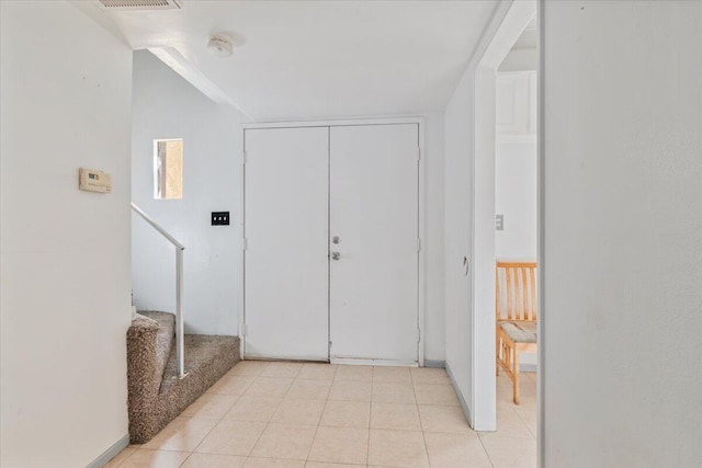 entryway featuring light tile patterned flooring, visible vents, and stairs