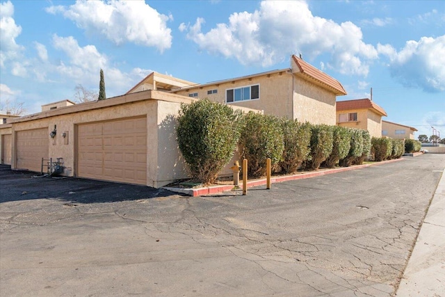 view of side of property featuring stucco siding and community garages