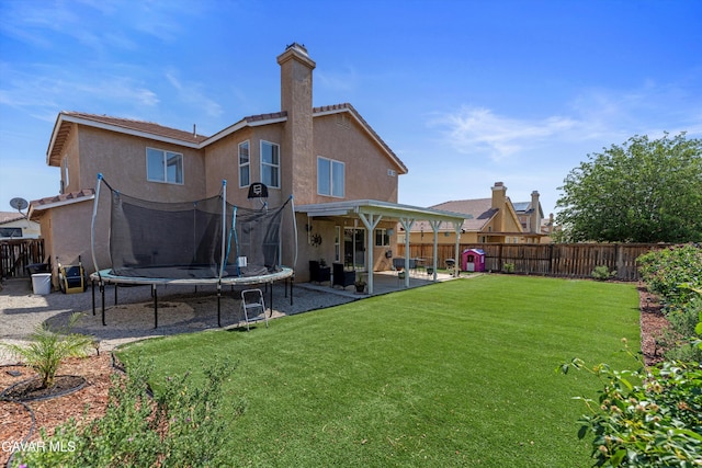 3616 Glenridge Ave, Rosamond, CA 93560 - back of house featuring a trampoline, a patio area, stucco siding, a fenced backyard, and a chimney