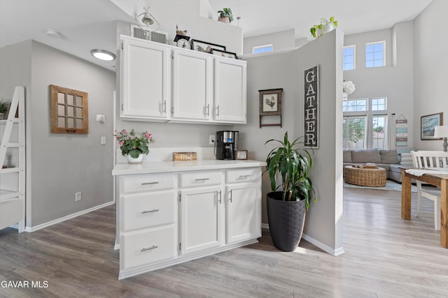 3616 Glenridge Ave, Rosamond, CA 93560 - kitchen with light countertops, white cabinetry, light wood-style flooring, and a high ceiling