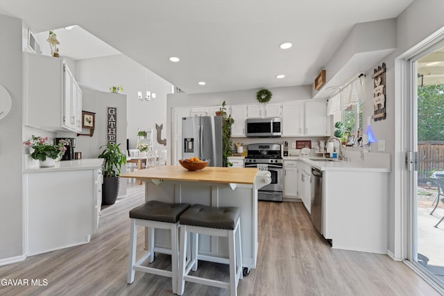 3616 Glenridge Ave, Rosamond, CA 93560 - kitchen with appliances with stainless steel finishes, light wood-type flooring, a breakfast bar area, white cabinets, and a chandelier