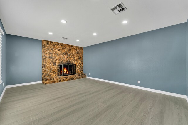 unfurnished living room with light hardwood / wood-style floors and a stone fireplace