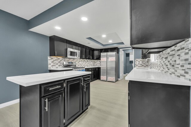 kitchen featuring appliances with stainless steel finishes, light wood-type flooring, a kitchen breakfast bar, and sink