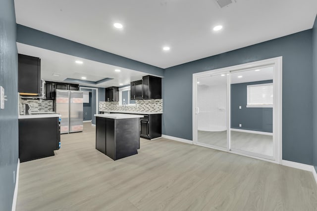 kitchen featuring backsplash, stainless steel refrigerator, a center island, and light hardwood / wood-style floors