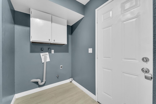 laundry area with electric dryer hookup, hookup for a gas dryer, light hardwood / wood-style floors, and cabinets