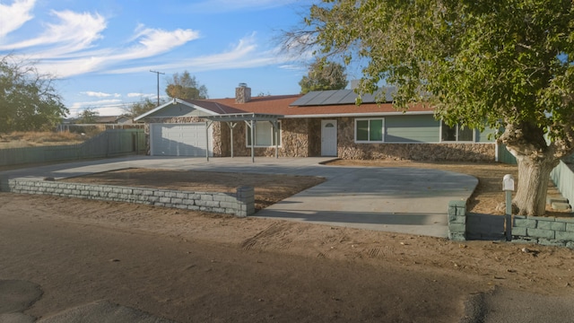 ranch-style home featuring a garage and solar panels