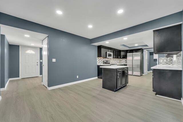 kitchen with tasteful backsplash, a center island, light wood-type flooring, and appliances with stainless steel finishes