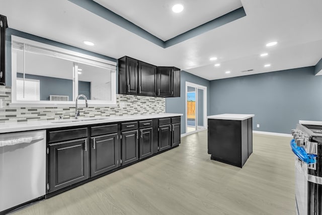 kitchen with sink, decorative backsplash, light wood-type flooring, appliances with stainless steel finishes, and a tray ceiling