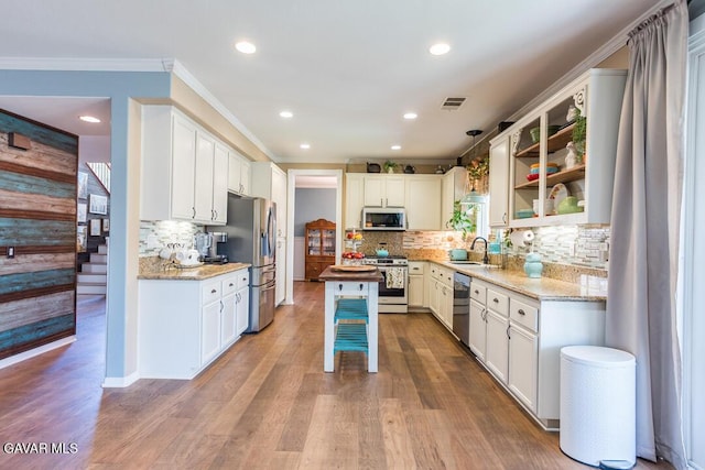 3455 Pine Mist Ct, Rosamond, CA 93560 - kitchen with stainless steel appliances, crown molding, light stone counters, decorative backsplash, and white cabinetry