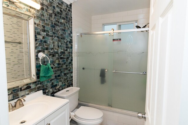 bathroom with backsplash, vanity, toilet, and walk in shower