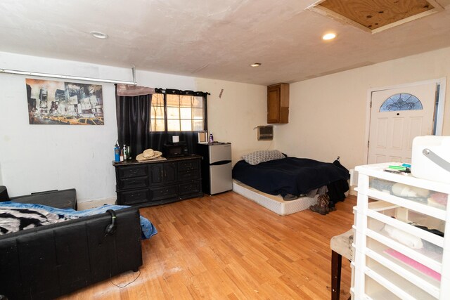 bedroom with stainless steel refrigerator and light hardwood / wood-style flooring