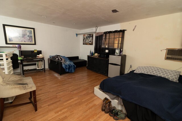 bedroom with wood-type flooring and white refrigerator