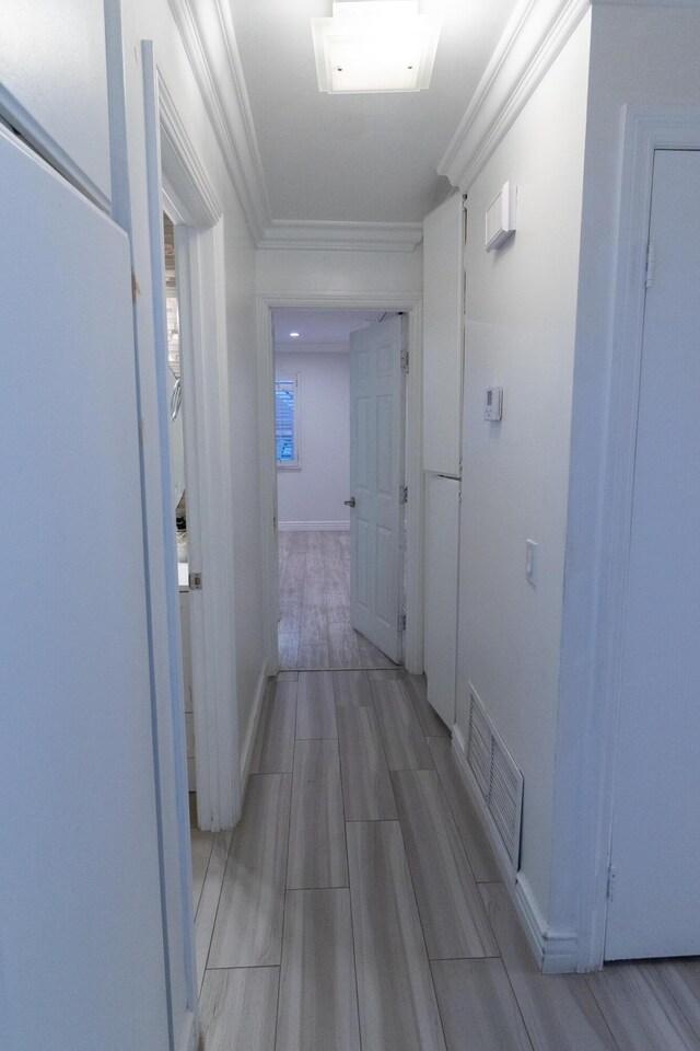 hall featuring light hardwood / wood-style floors and ornamental molding
