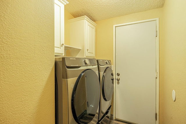 laundry room featuring a textured ceiling, cabinet space, a textured wall, and washing machine and clothes dryer