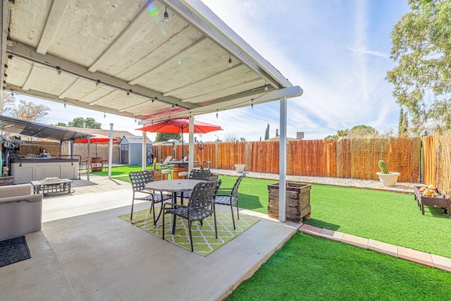 view of patio / terrace featuring a fenced backyard, a shed, outdoor dining space, and an outdoor structure