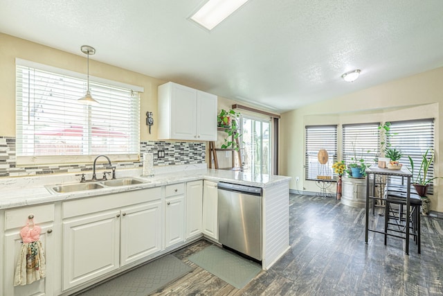 kitchen featuring lofted ceiling, a peninsula, stainless steel dishwasher, white cabinetry, and a sink