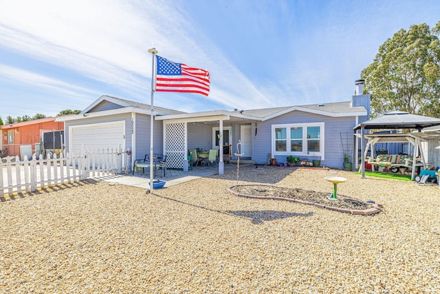 view of front facade featuring a gazebo, a patio area, a garage, and fence