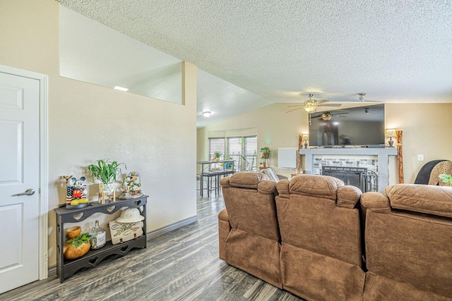 living room featuring wood finished floors, a fireplace, lofted ceiling, and a textured ceiling