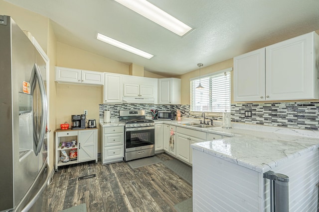 kitchen featuring a sink, appliances with stainless steel finishes, a peninsula, lofted ceiling, and dark wood-style flooring