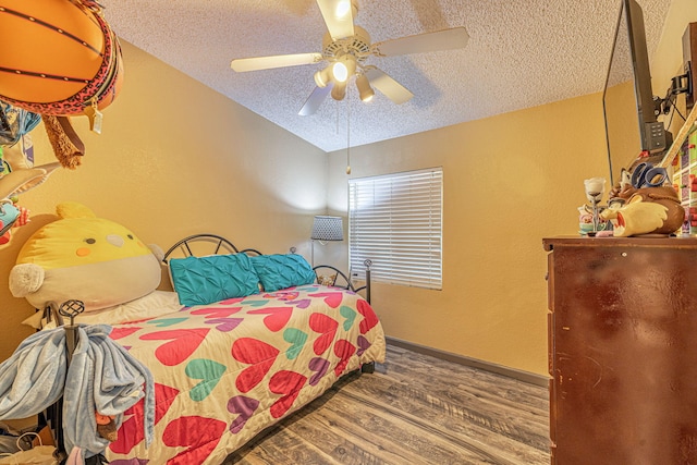 bedroom with ceiling fan, baseboards, vaulted ceiling, wood finished floors, and a textured ceiling