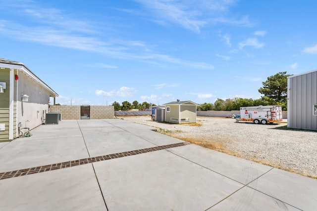 fenced backyard featuring a storage shed, an outdoor structure, a patio, and central air condition unit