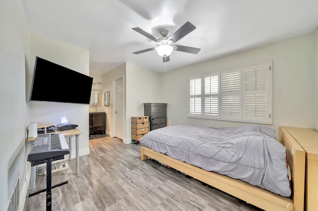 bedroom featuring baseboards, visible vents, a ceiling fan, ensuite bath, and wood finished floors