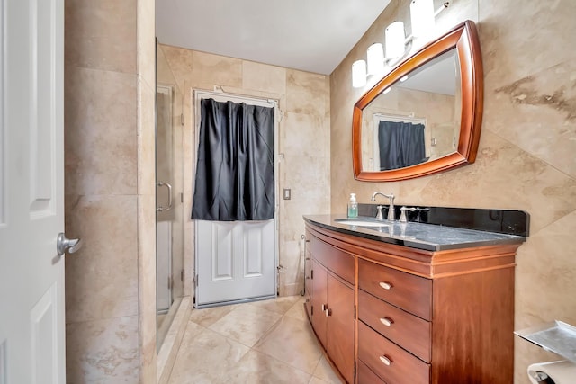 bathroom with tile patterned floors, a shower stall, tile walls, and vanity