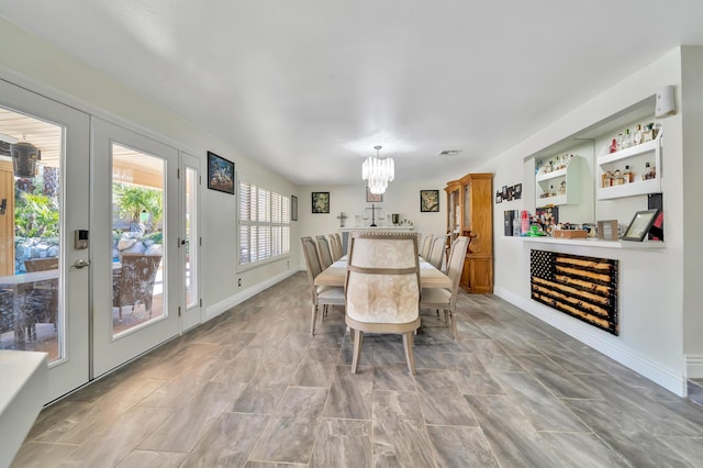 dining space featuring french doors, a dry bar, visible vents, a chandelier, and baseboards