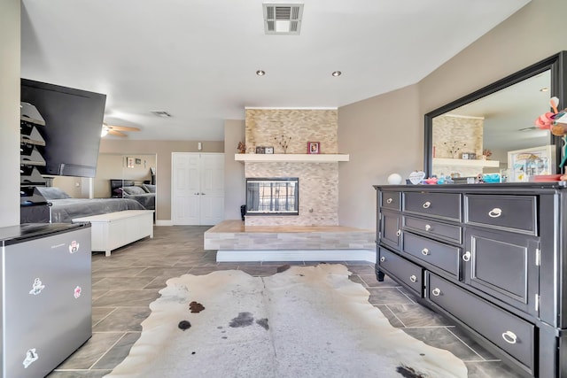 bedroom with freestanding refrigerator, visible vents, and a multi sided fireplace