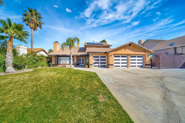 view of front facade with an attached garage, solar panels, concrete driveway, a gate, and a front lawn