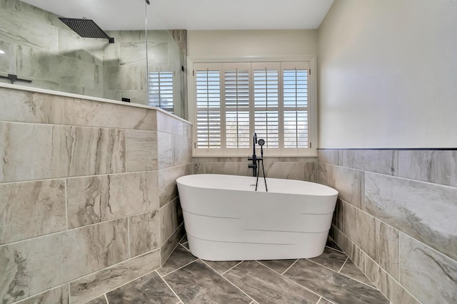 bathroom with a freestanding tub, walk in shower, and tile walls