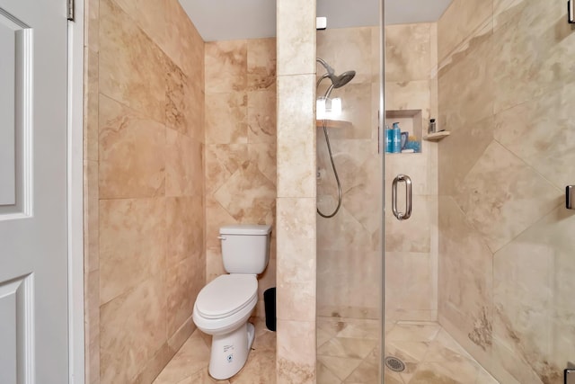 full bath featuring toilet, a stall shower, and tile walls