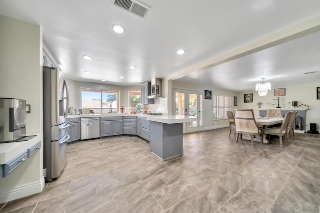 kitchen featuring gray cabinetry, a peninsula, visible vents, light countertops, and appliances with stainless steel finishes