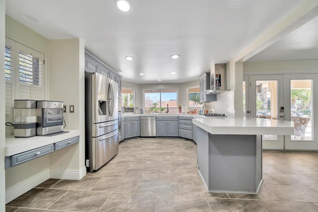 kitchen featuring appliances with stainless steel finishes, gray cabinets, light countertops, and a peninsula