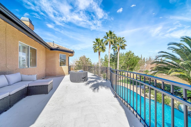 exterior space featuring a balcony, an outdoor living space, and a fenced in pool