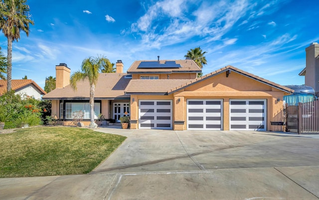 view of front of house with driveway, solar panels, an attached garage, a front lawn, and stucco siding