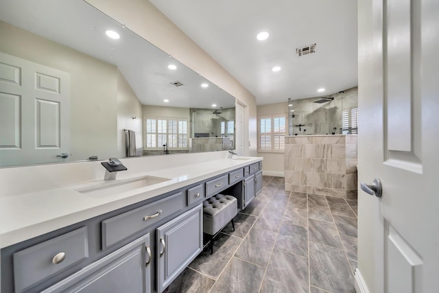 bathroom featuring a walk in shower, double vanity, a sink, and visible vents