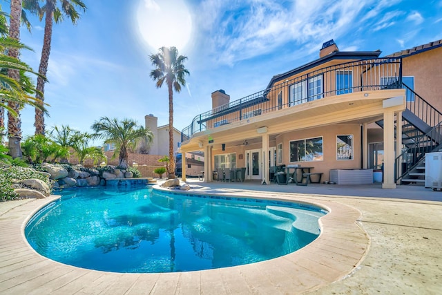 outdoor pool with a patio area, stairway, and a ceiling fan