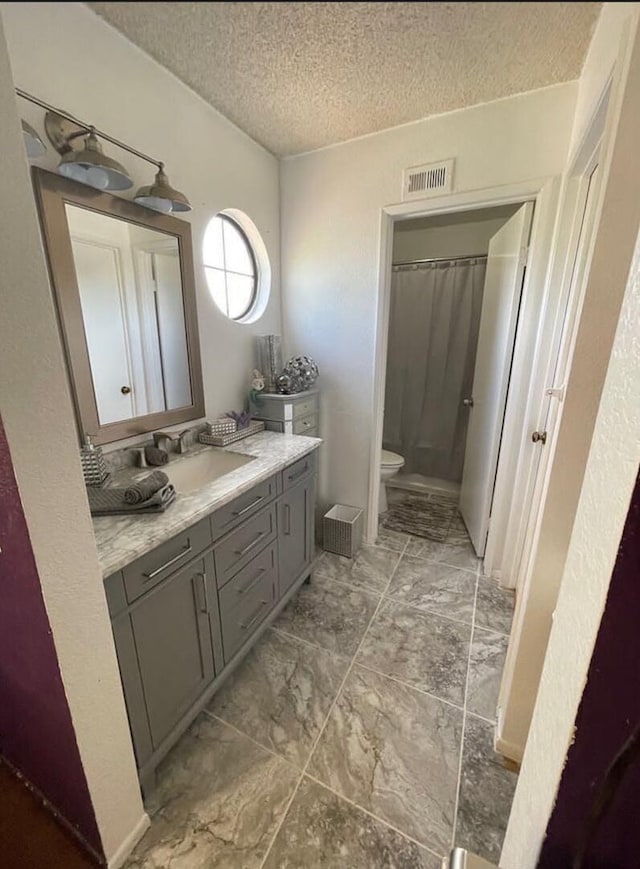 bathroom featuring a shower with shower curtain, vanity, toilet, and a textured ceiling