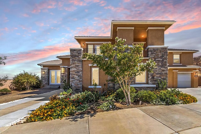 view of front facade with a garage, stone siding, concrete driveway, and stucco siding