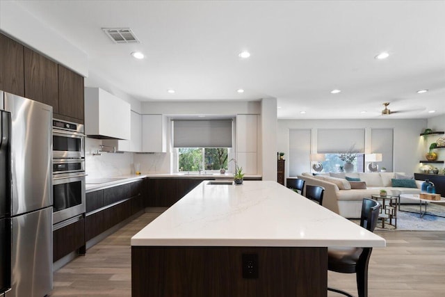 kitchen with visible vents, dark brown cabinets, modern cabinets, and freestanding refrigerator