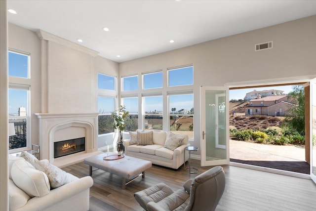 living area with a wealth of natural light, visible vents, a premium fireplace, and wood finished floors