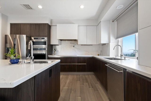 kitchen featuring stainless steel appliances, modern cabinets, a sink, and visible vents