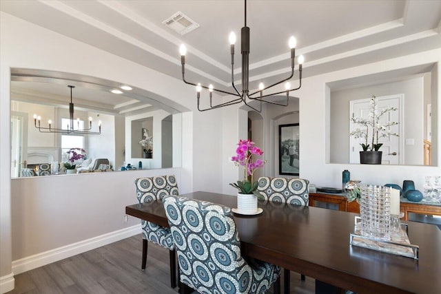 dining room featuring visible vents, arched walkways, wood finished floors, an inviting chandelier, and a tray ceiling