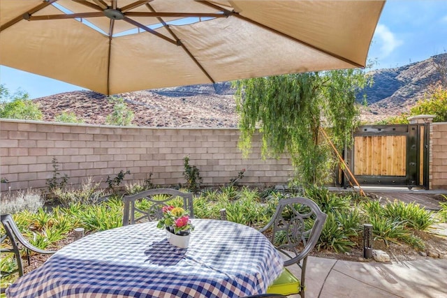 view of patio / terrace featuring a mountain view, a fenced backyard, and a gate