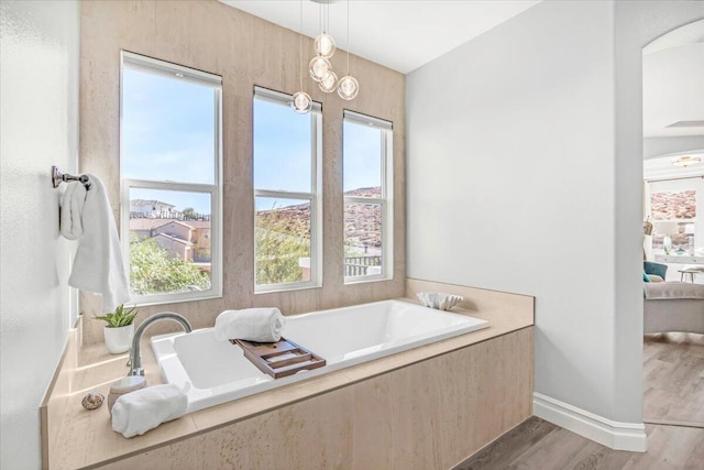 full bath featuring a garden tub, ensuite bath, baseboards, and wood finished floors