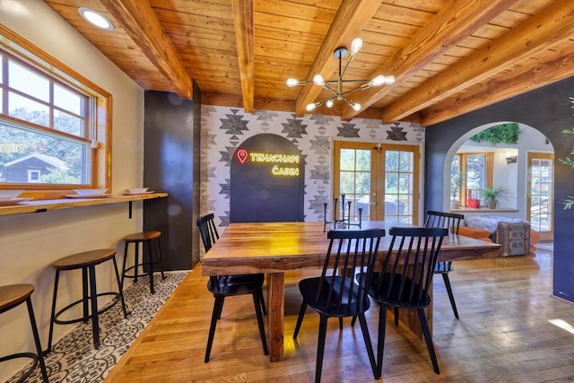 dining room with french doors, an inviting chandelier, beamed ceiling, wood ceiling, and hardwood / wood-style flooring