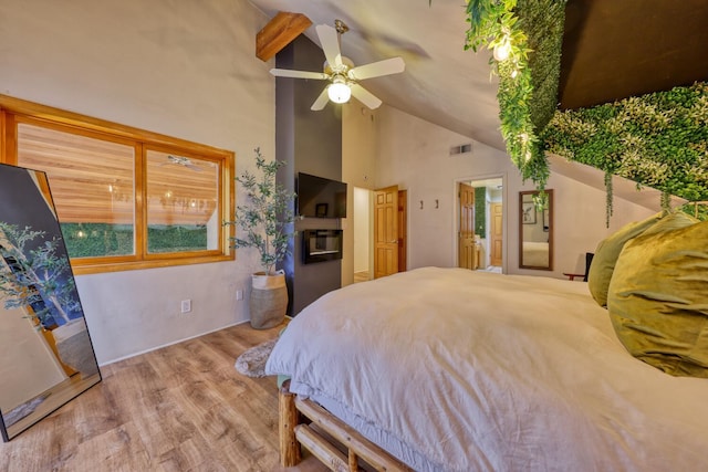 bedroom with beam ceiling, connected bathroom, ceiling fan, light hardwood / wood-style flooring, and high vaulted ceiling